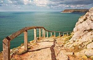 Dan Santilo glass placemat featuring a scenic cliff path overlooking the ocean.
