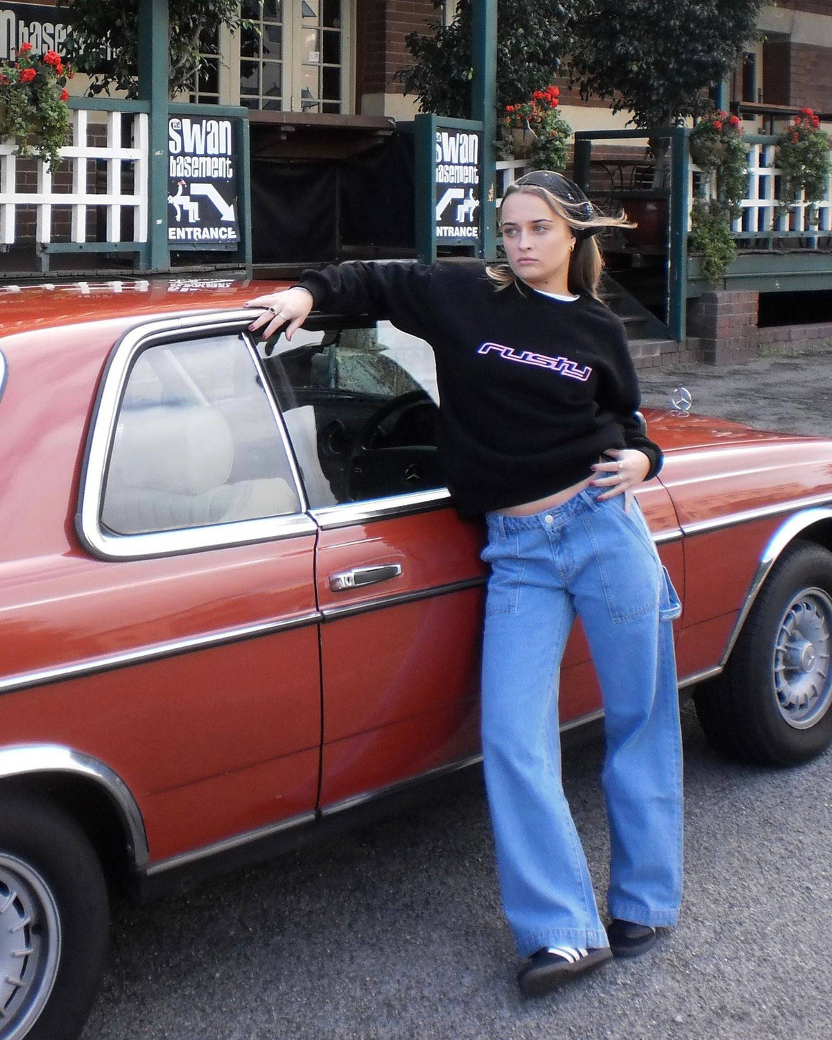 Model wearing Rusty Billie Low Rise Carpenter Pant leaning on a vintage car.
