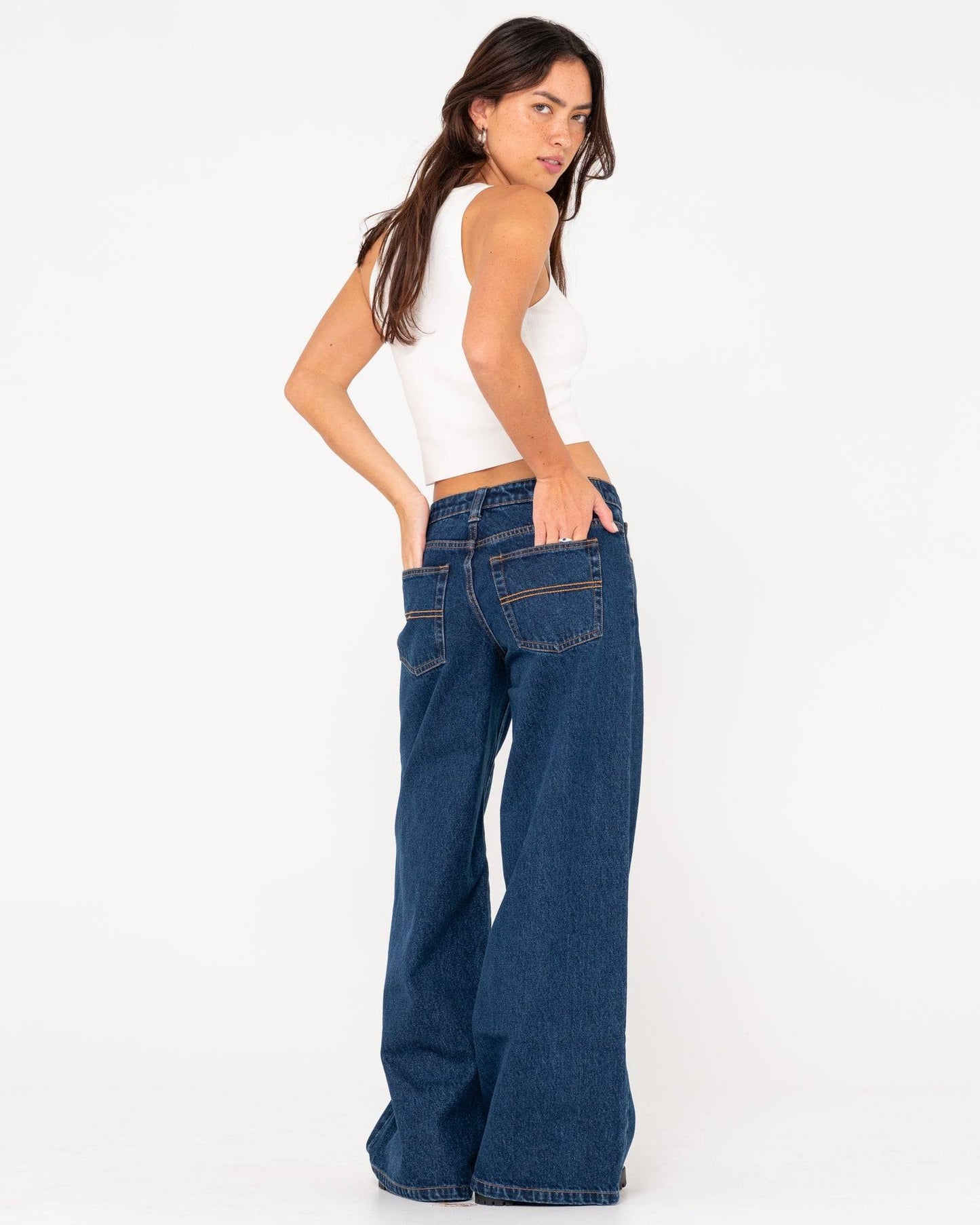 Side-back view of Rusty Low Rise Super Wide Leg Jean styled with a white crop top.