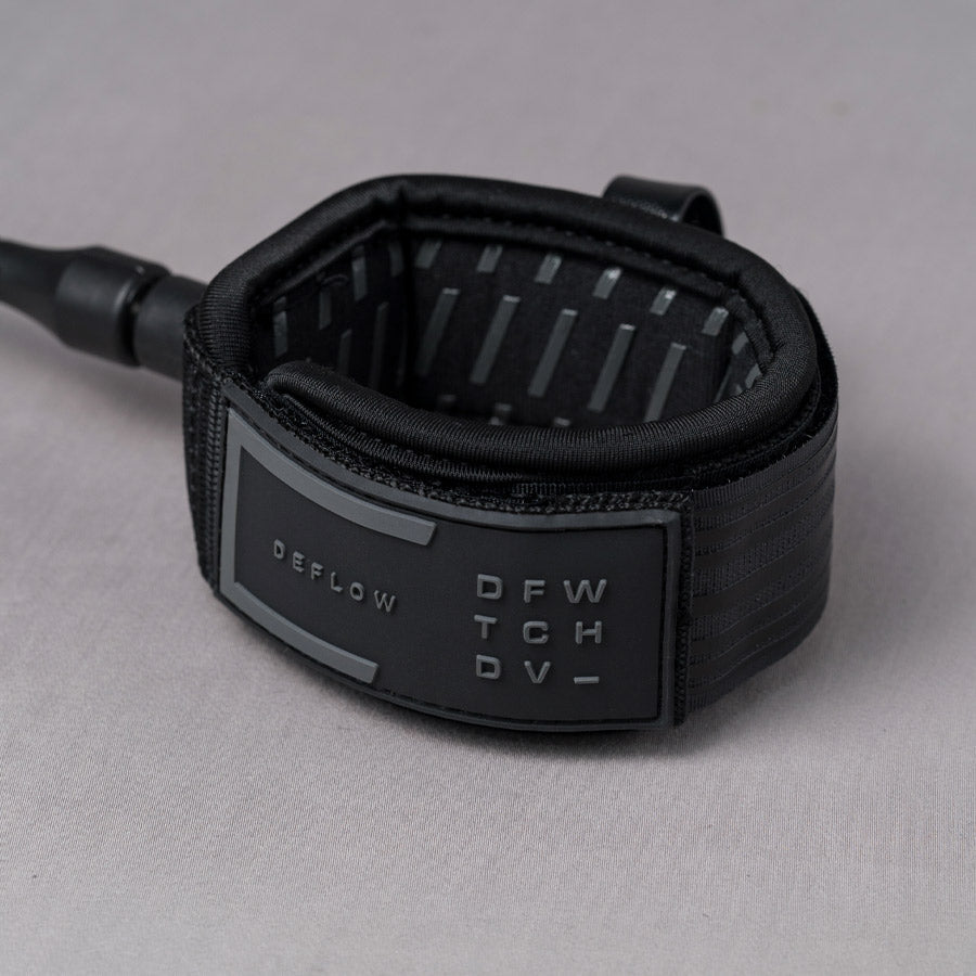 Close-up of Deflow 9ft 7mm black knee leash with padded cuff and branding.