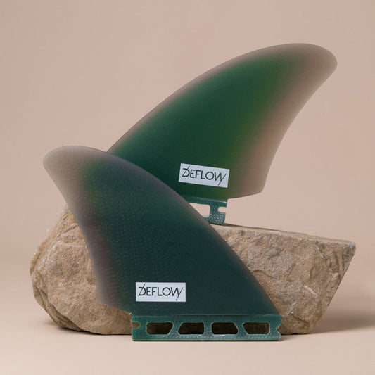 Set of Deflow Mid Green twin fins with single tab design on a rock.