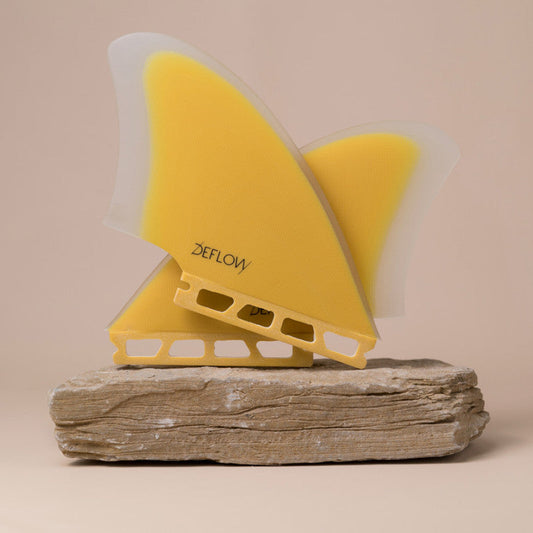 Pair of Deflow Palm twin fins in mustard color on a stone base.