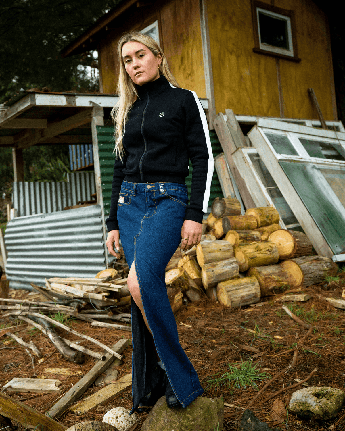 Rusty Celeste low-rise denim maxi skirt styled with a black jacket outdoors.