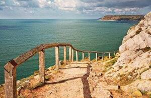 Dan Santilo glass placemat featuring a scenic cliff path overlooking the ocean.