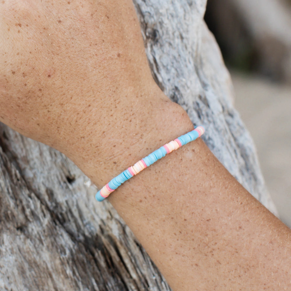 Colorful clay beaded bracelet with pastel tones worn on a wrist.