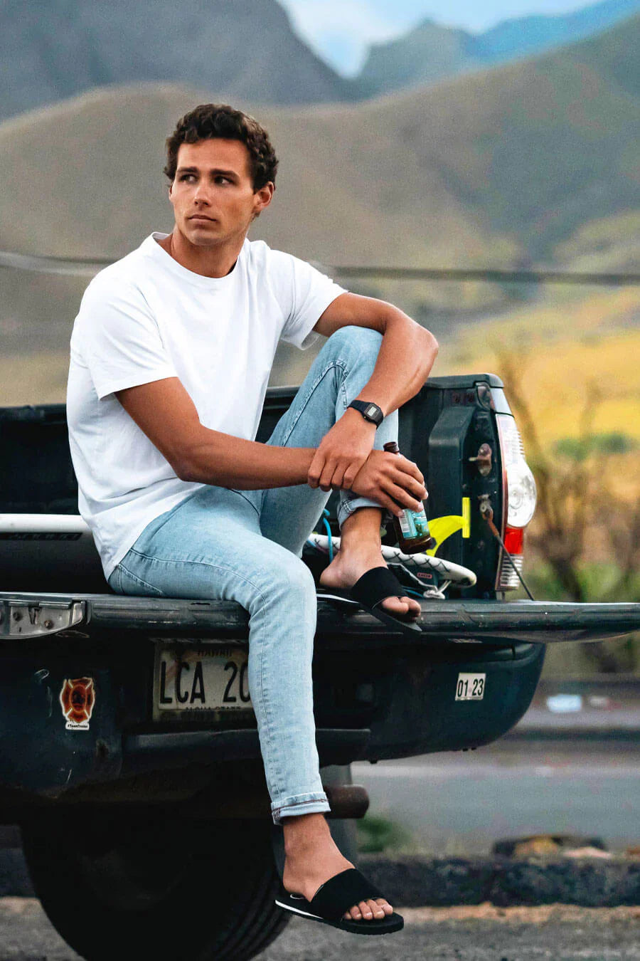 Man sitting on truck wearing FoamLife Tarlan Slide black sliders.