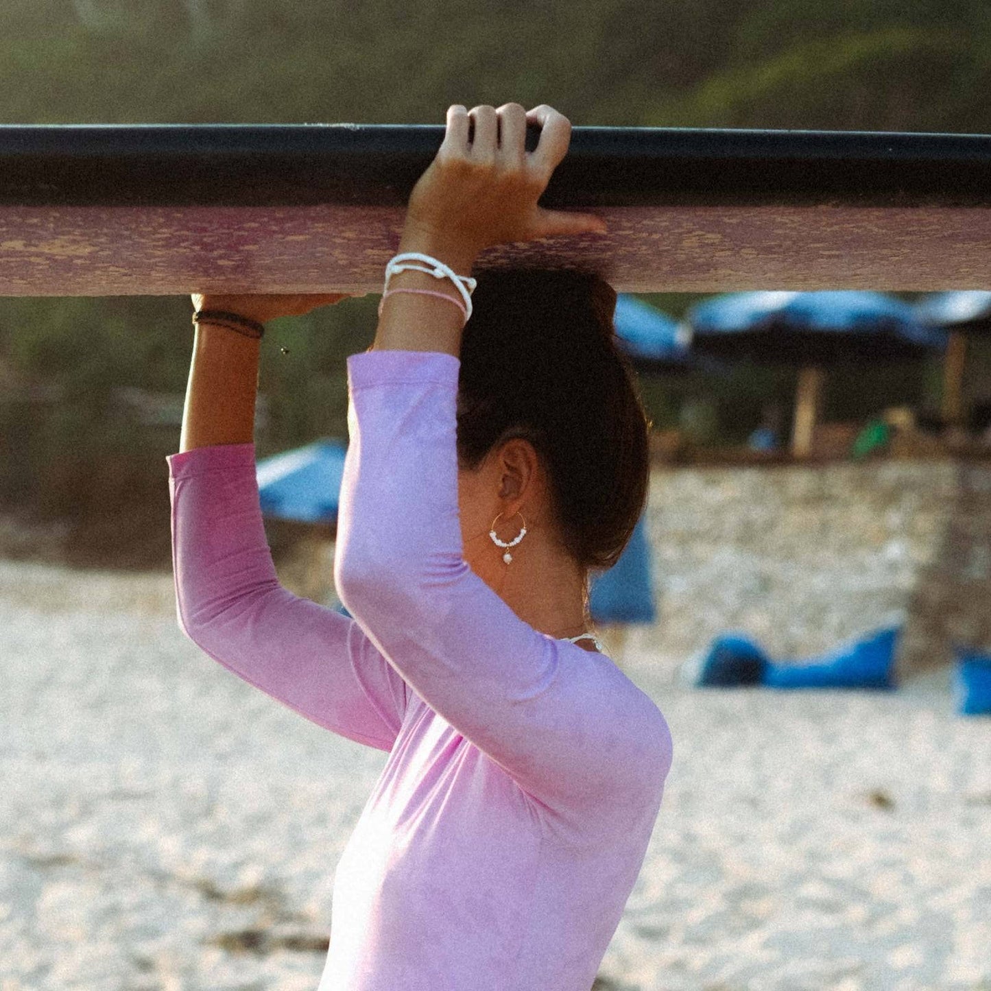 GIADA GEGAMBAR WIRE HOOP EARRINGS worn by surfer on beach, styled with casual beachwear and layered jewelry.