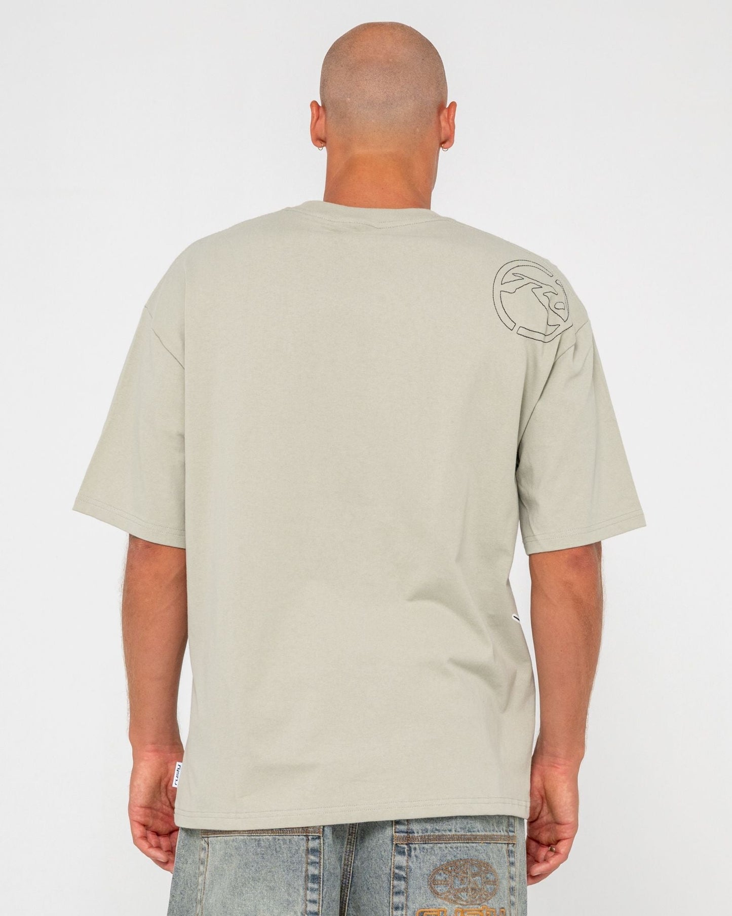 Back view of beige men's graphic t-shirt with logo on shoulder, short sleeves