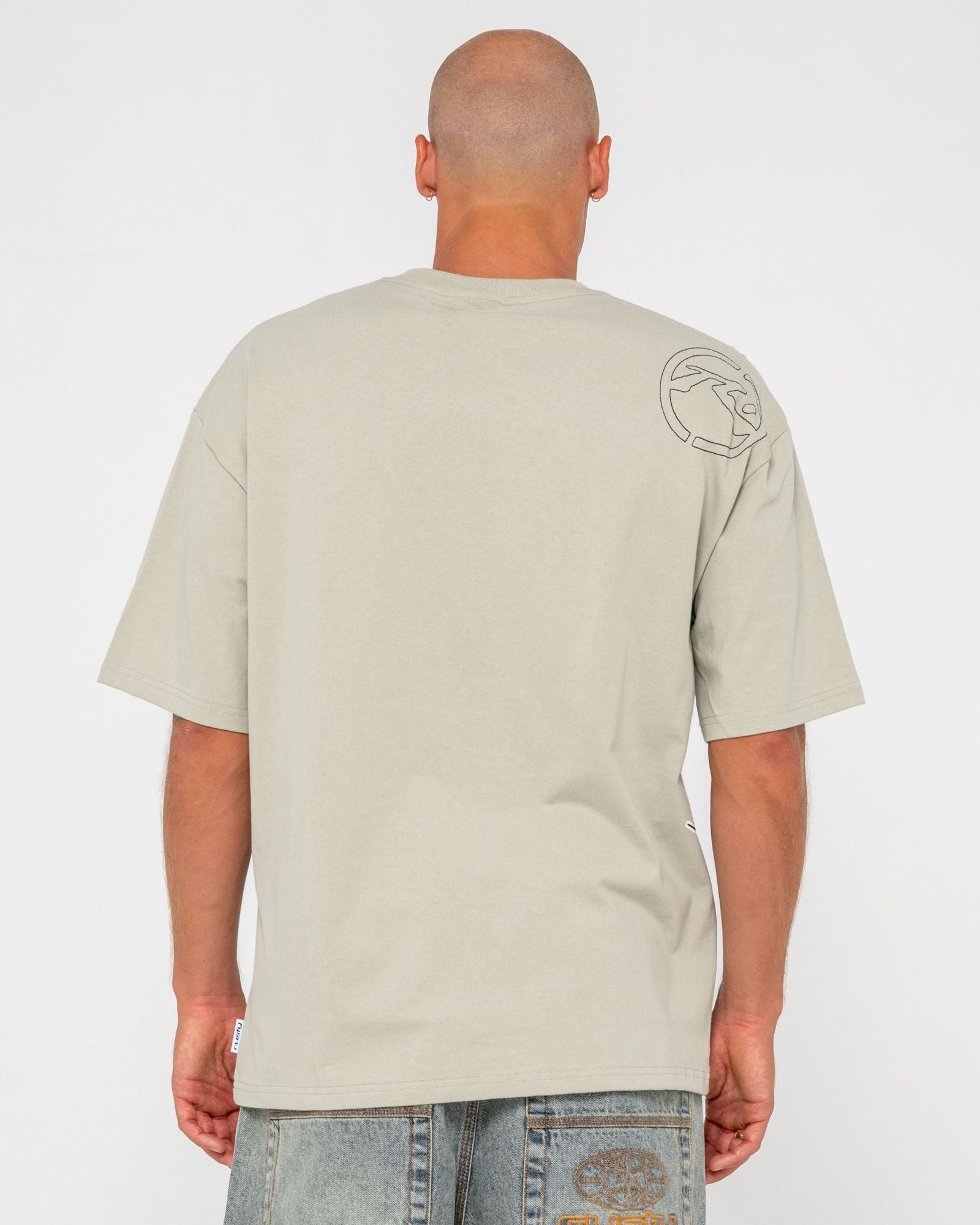 Back view of beige men's graphic t-shirt with logo on shoulder, short sleeves