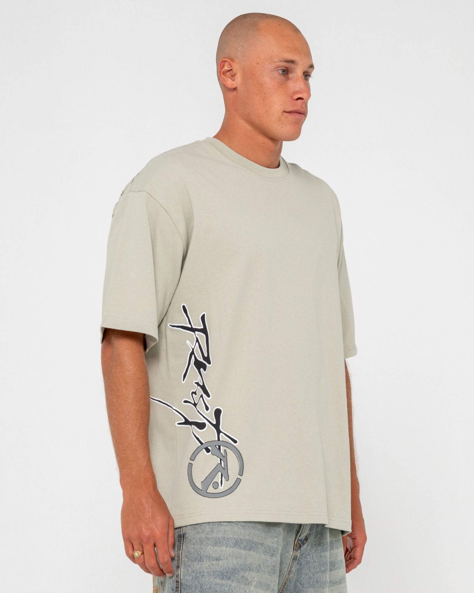 Close-up of logo on front of beige men's t-shirt, short sleeve design