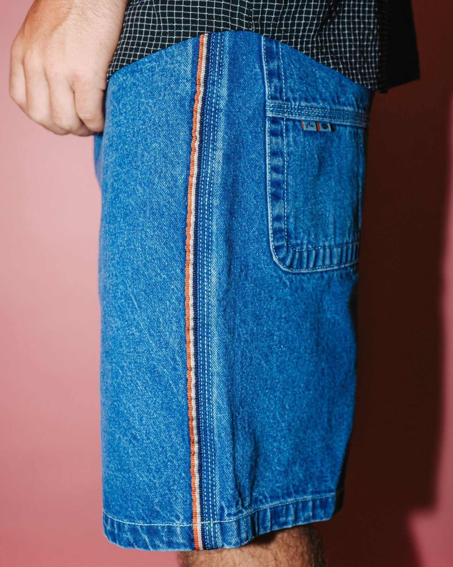 Side view of men's denim walkshorts with orange seam detail
