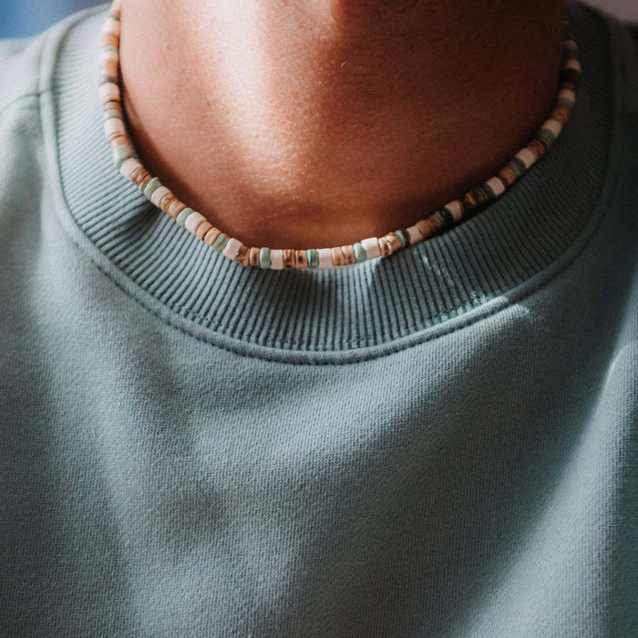 Man wearing Pineapple Island Laut turquoise wood necklace with a green sweatshirt.