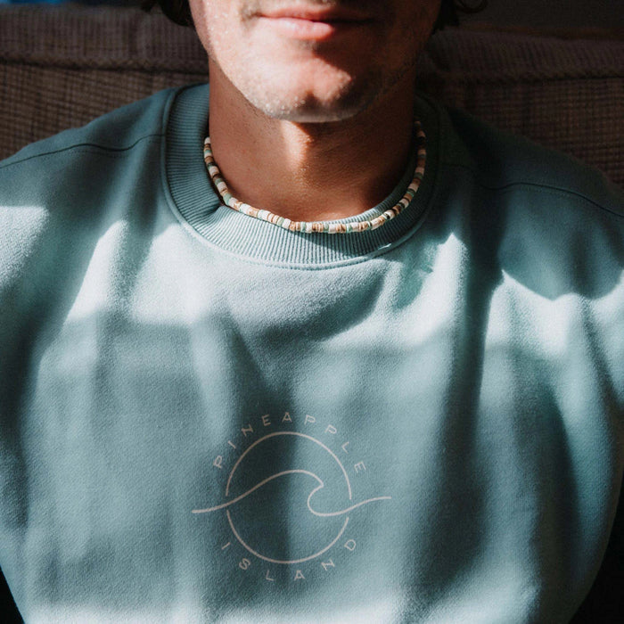 Man in Pineapple Island sweatshirt wearing Laut turquoise wood necklace.