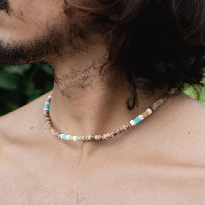 Close-up of Nomad disc necklace with natural and turquoise bead design on a model.