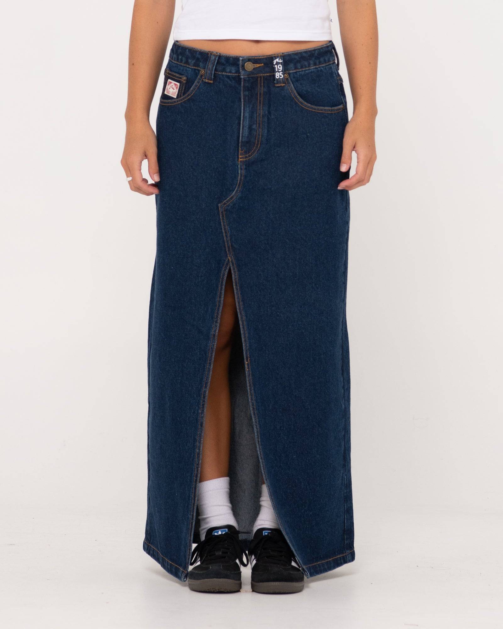 Rusty Celeste low-rise denim maxi skirt with front slit, styled casually.