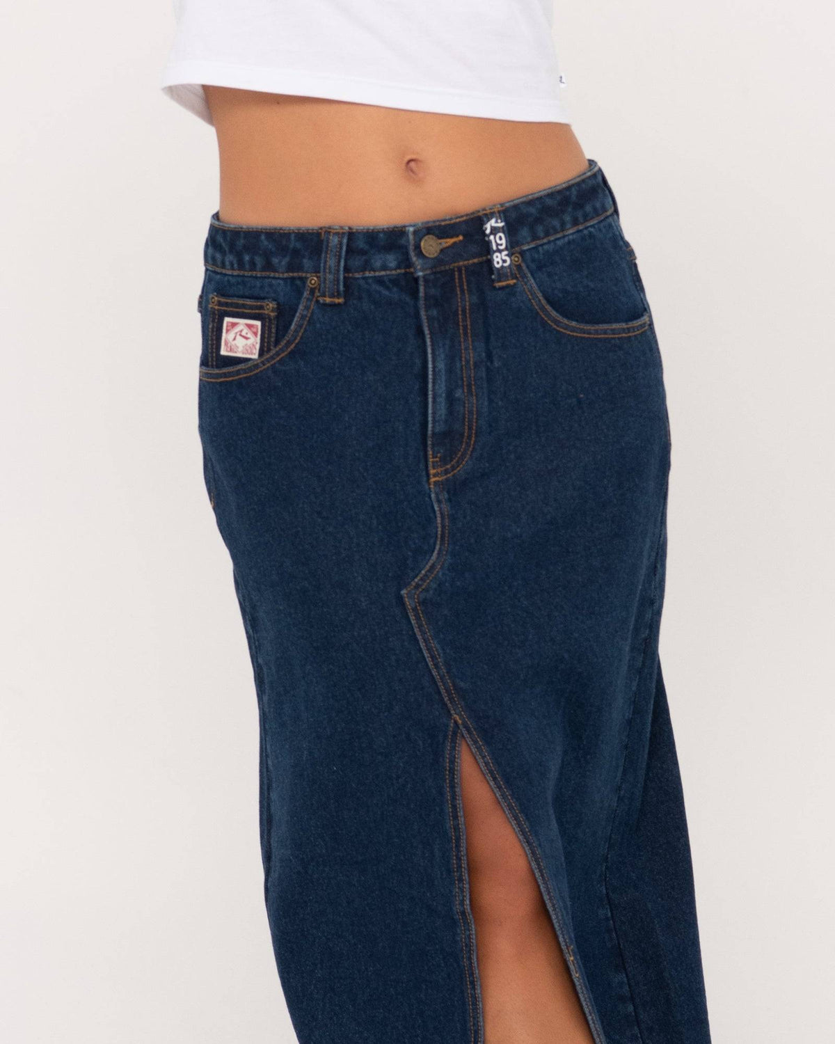 Close-up of Rusty Celeste denim maxi skirt highlighting front slit and details.