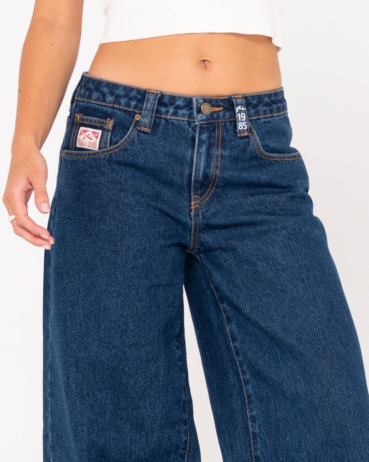 Close-up of front details on Rusty Low Rise Super Wide Leg Jean with logo patch.