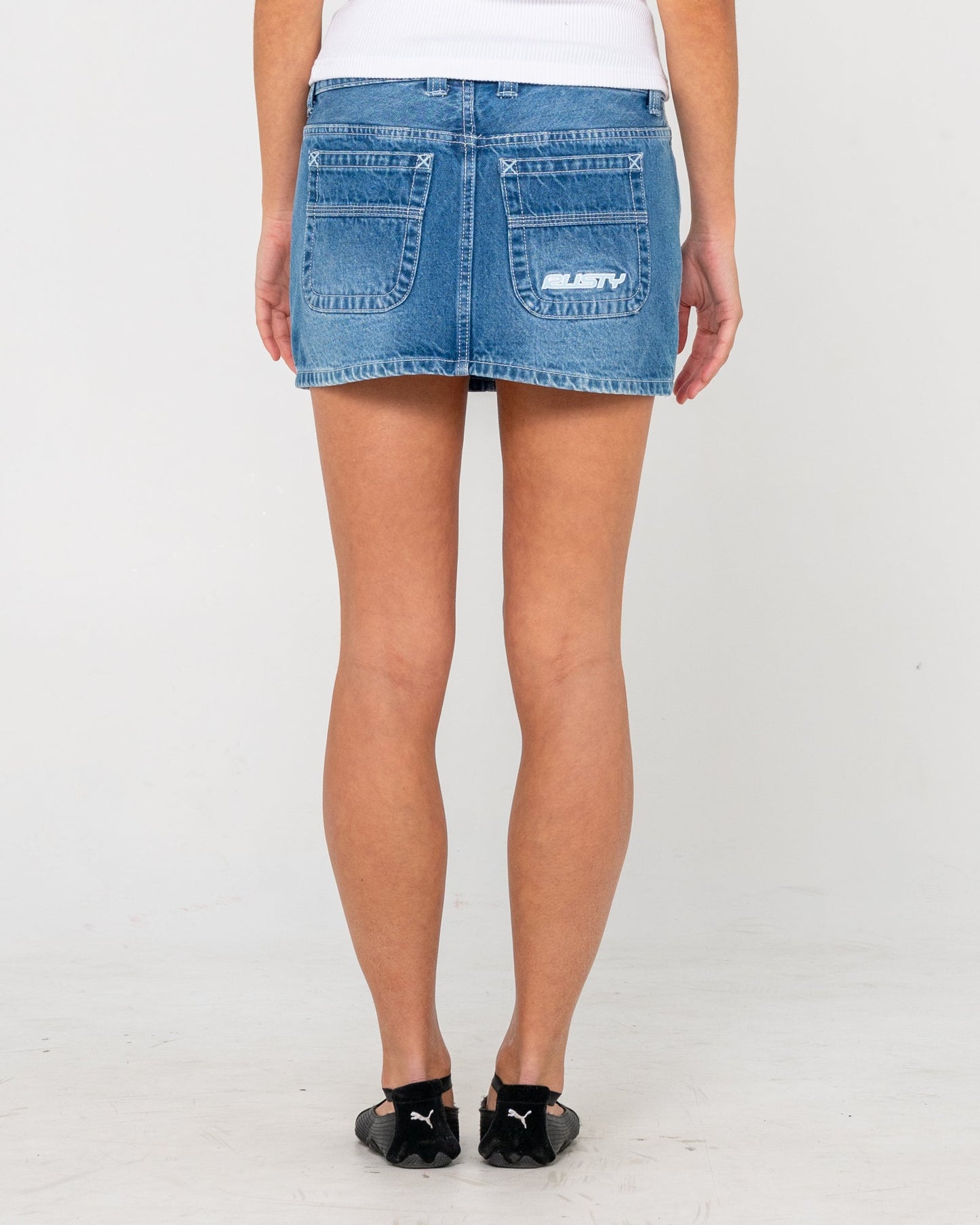 Back view of blue denim mini skirt with logo embroidery for women