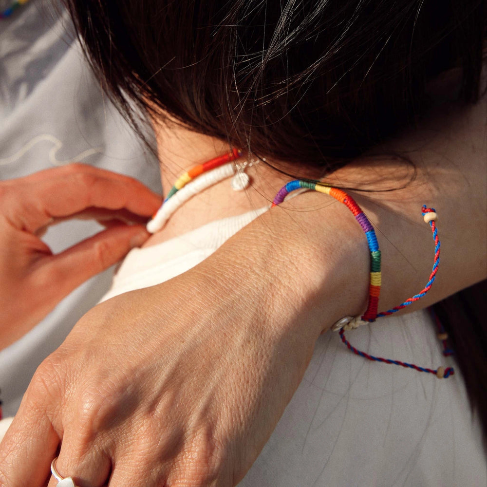 Close-up of Pineapple Island pride bracelet on wrist during an embrace.