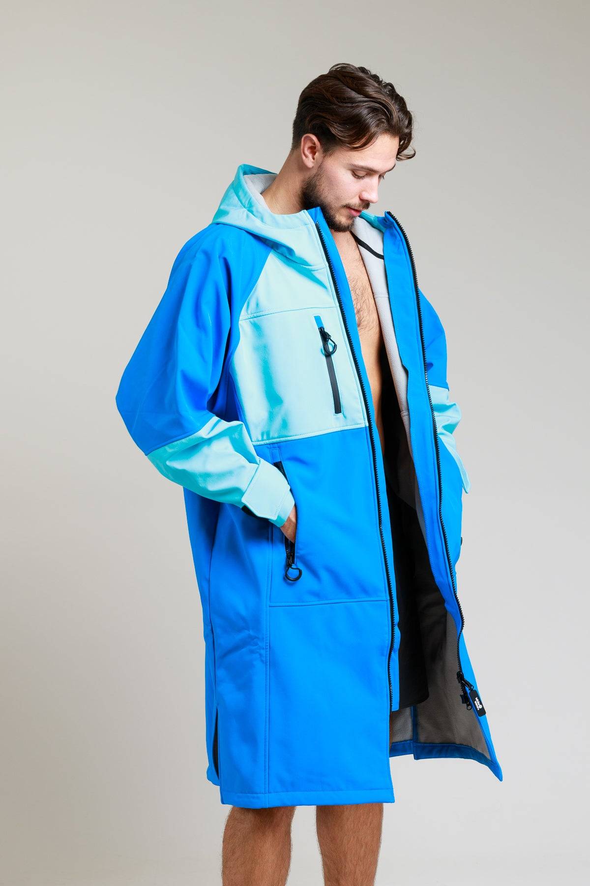 Man showcasing the interior lining of the White Water cobalt blue soft shell robe with hands in pockets.
