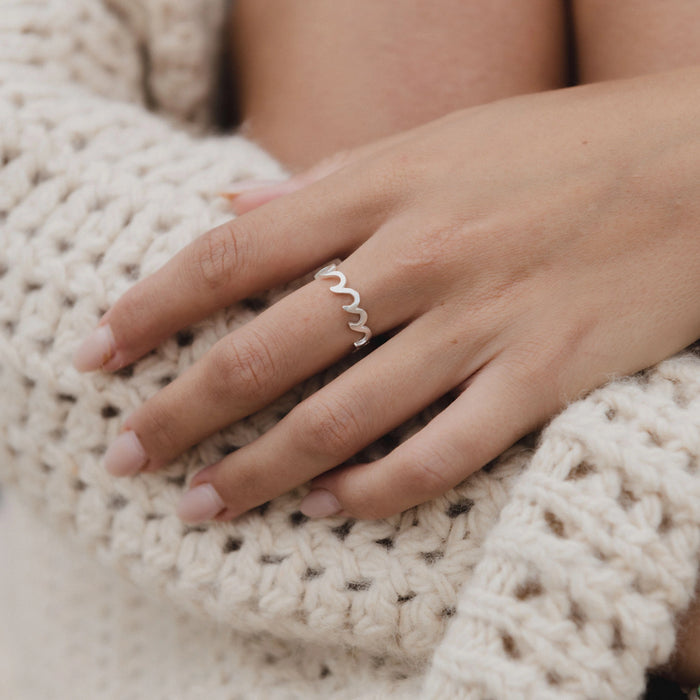 Silver Crashing Wave Ring displayed on hand with cozy knitwear.