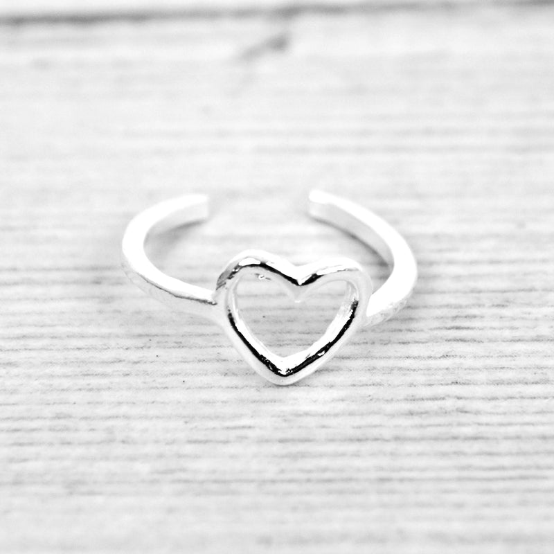 Silver hollow heart ring by Pineapple Island on a wooden background.