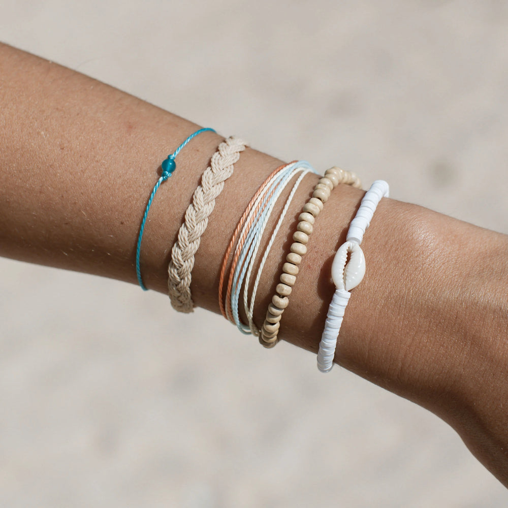 Stacked bracelets featuring coconut wood beads and shell accents on wrist.