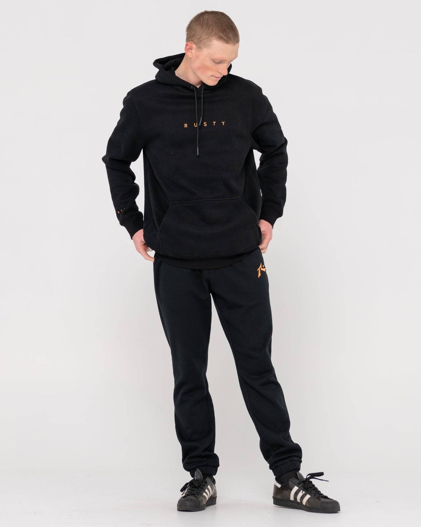 Full outfit view of Rusty Short Hooded Fleece - Standard Fit Hoodie in black, paired with matching joggers and sneakers.