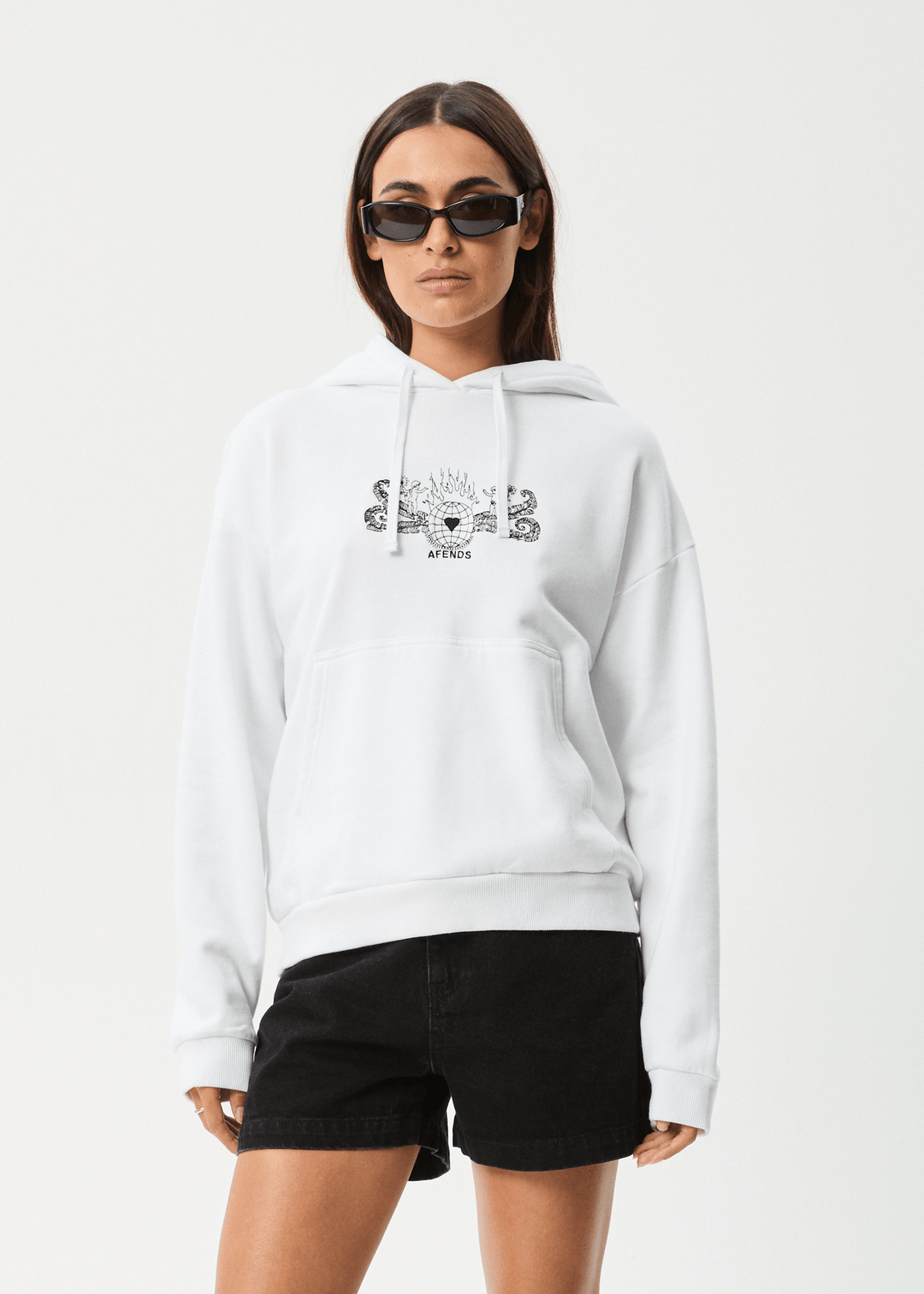 White oversized hoodie with black graphic artwork on front, drawstring hood, front pouch pocket, relaxed fit, worn by a female model with sunglasses