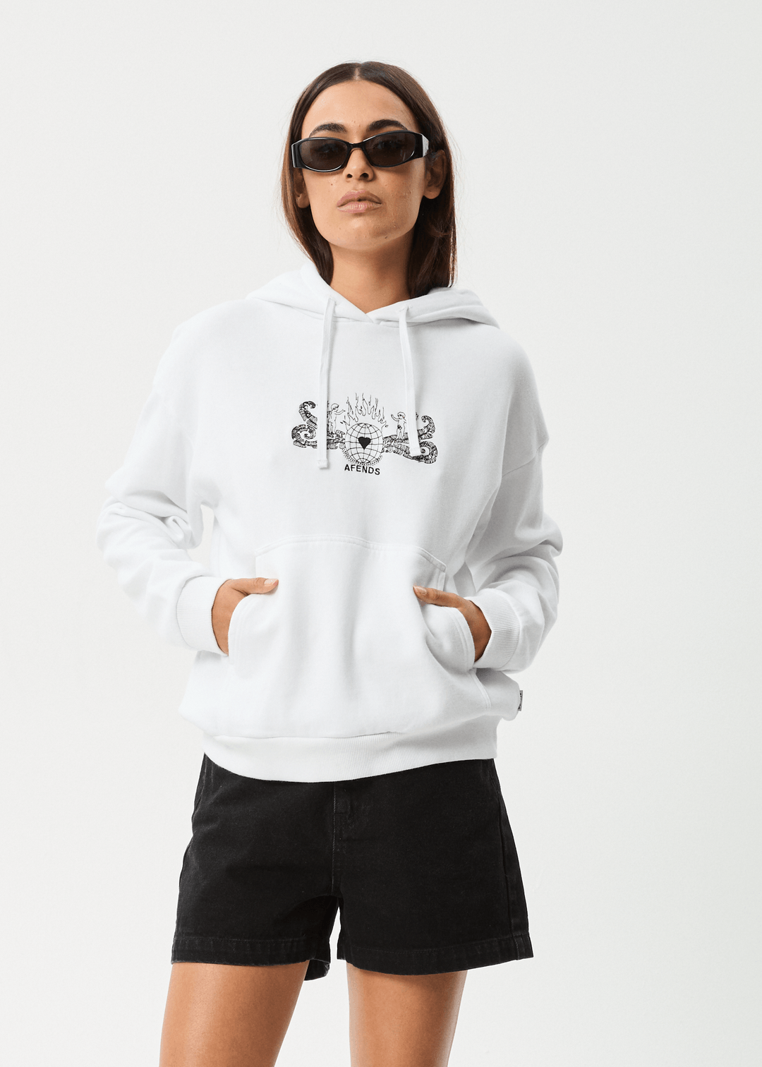 White Afends Bonfire hoodie with relaxed fit, front pouch pocket, drawstring hood, and printed contrast artwork, worn by a woman with sunglasses