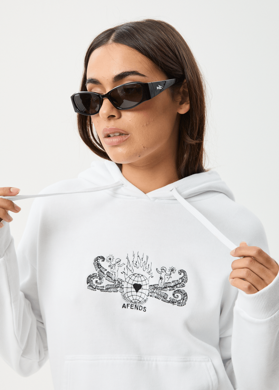 Model wearing black Afends Bonfire hoodie with printed graphic design, relaxed fit, and drawstring hood, styled with black sunglasses
