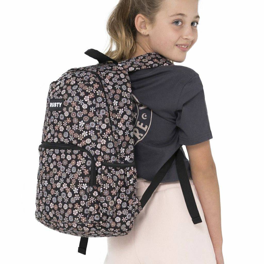 Rusty Indiana Backpack worn by a young girl, showcasing its floral design and comfortable straps.