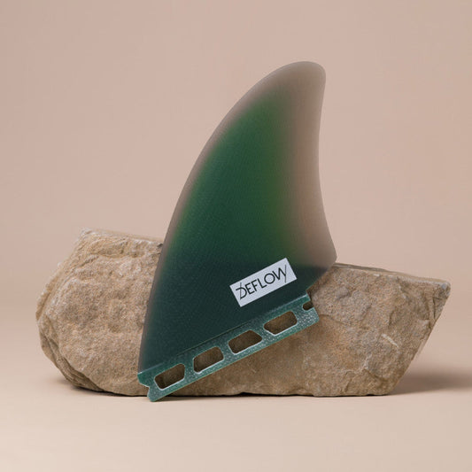 Deflow Mid Green twin fin with single tab design on a rock display.