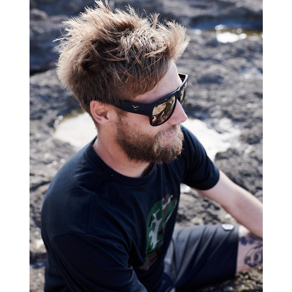 Man wearing I-Sea Nick I Waterman sunglasses with black rubber frame and copper mirror lenses outdoors.