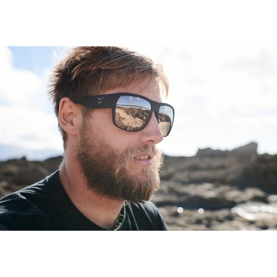 Profile view of man wearing I-Sea Nick I Waterman sunglasses with black rubber frame and copper mirror lenses.