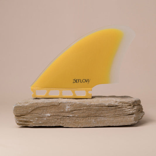 Deflow Palm twin fin in mustard color displayed on a stone base.