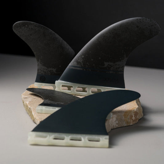 Deflow SUPRA QUATTRO M quad fins with sleek black design on stone.