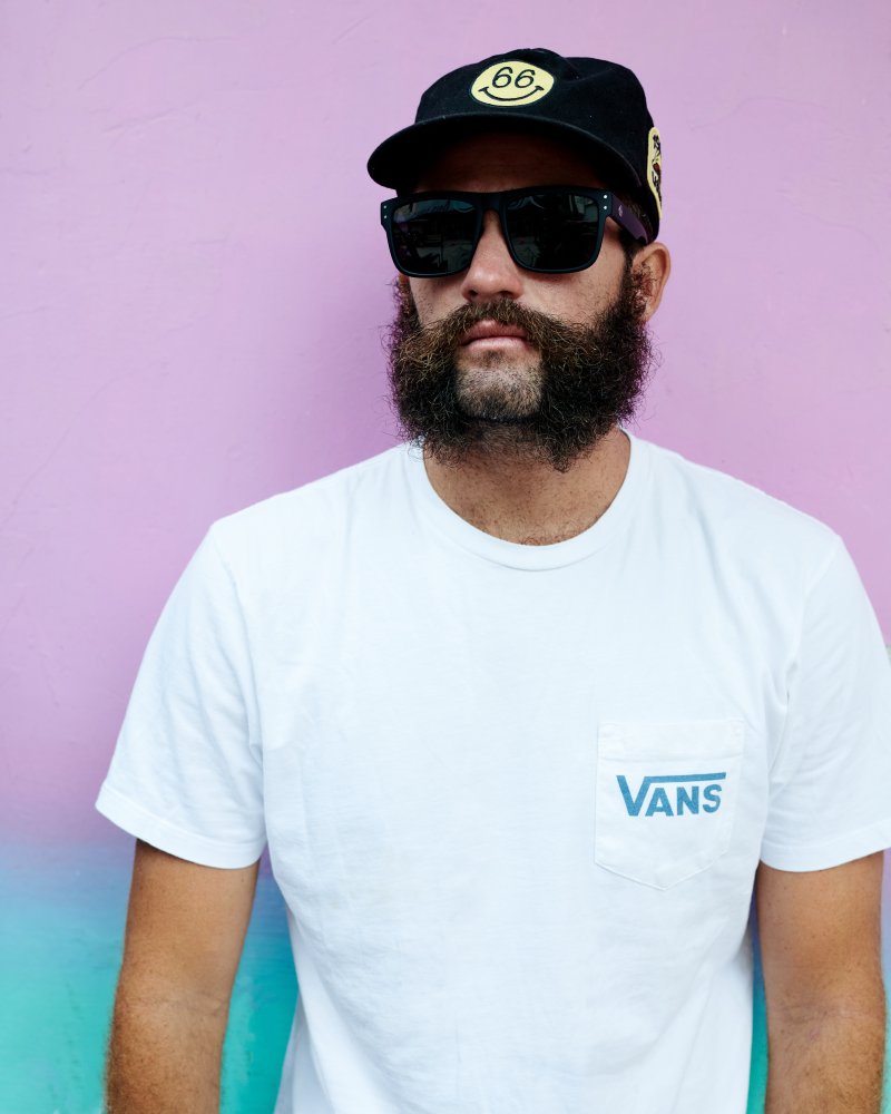 Man posing in I-Sea V-Lander black rubber sunglasses with smoke polarized lenses against a colorful background.